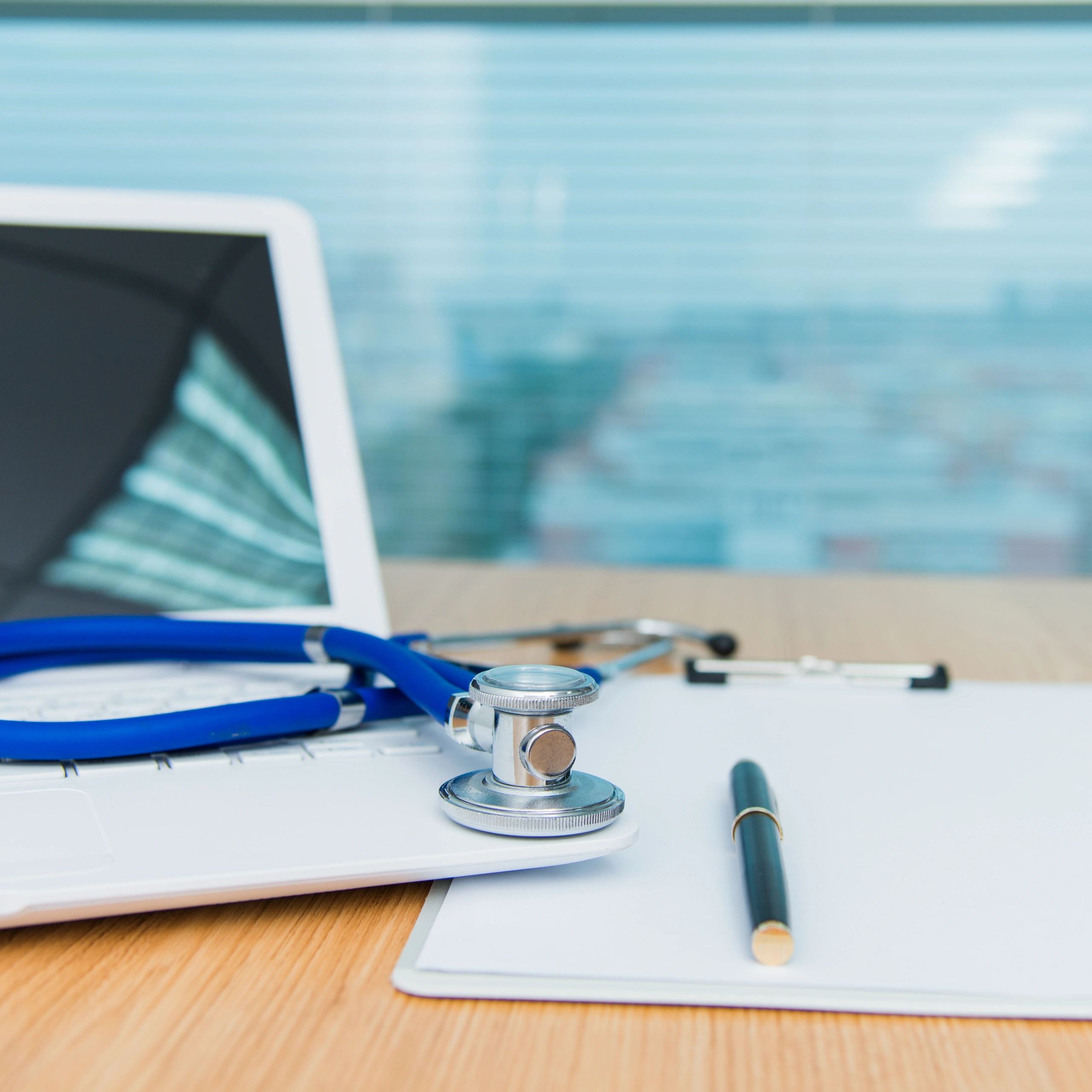 Medical document review workspace with laptop and clipboard